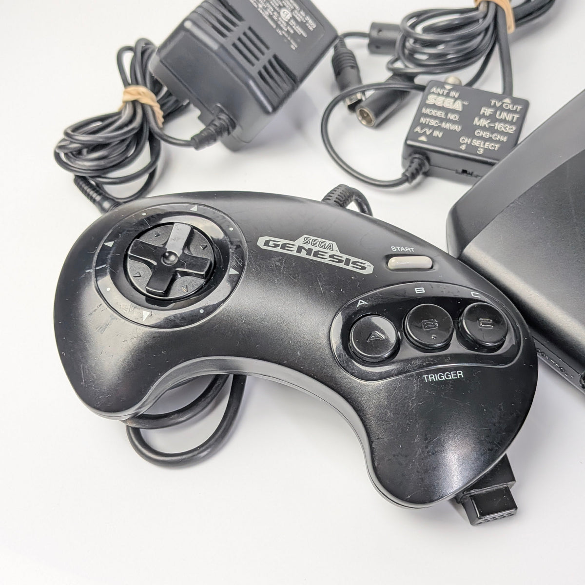 Sega Genesis controller with power adapter on a white background