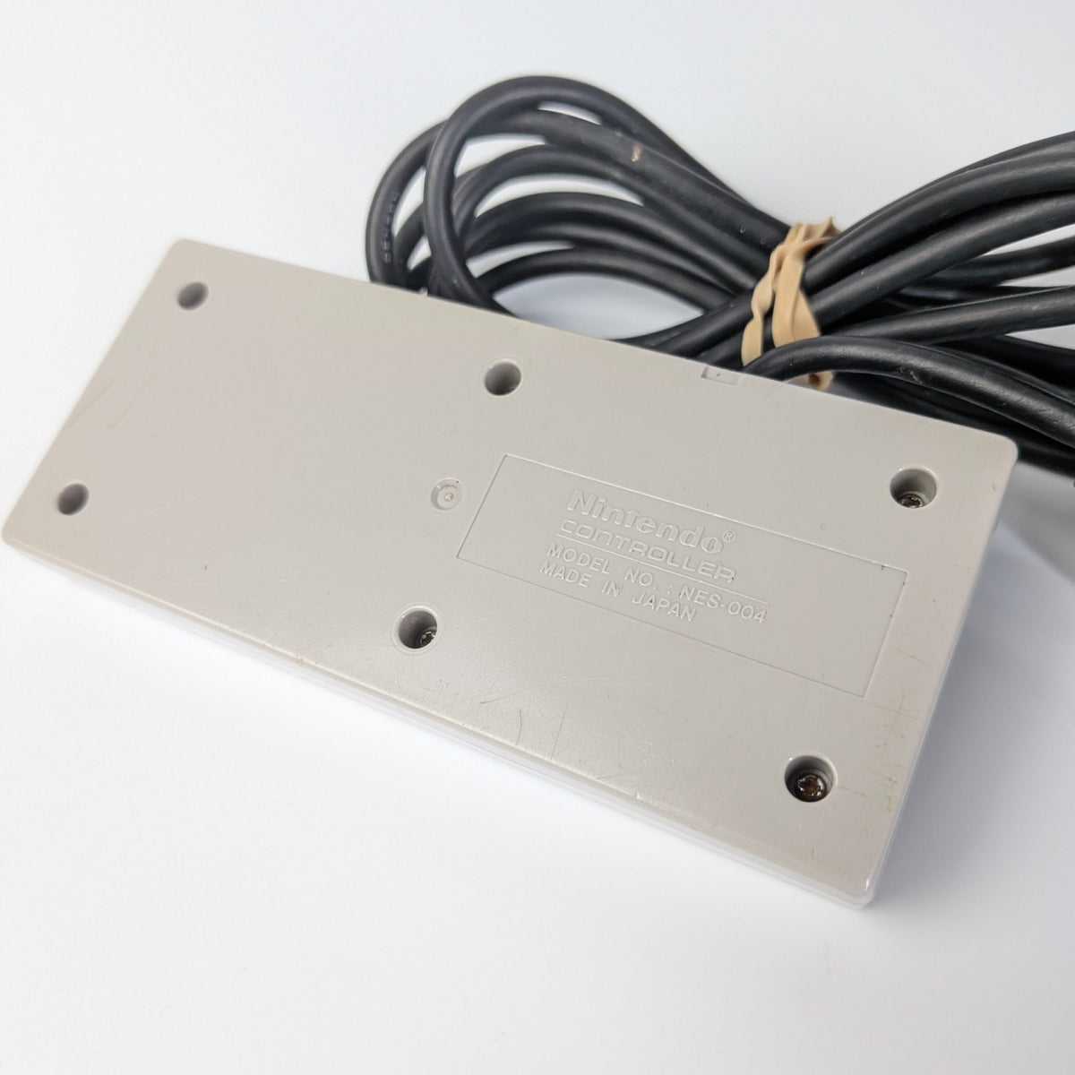 Rectangular metal plate with holes and a cable on a white background