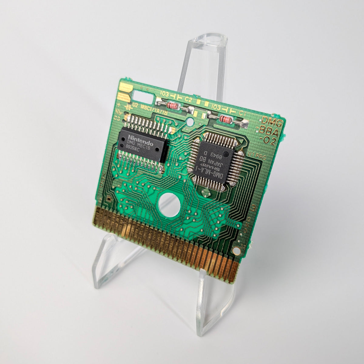 Green electronic circuit board on a clear stand against a white background