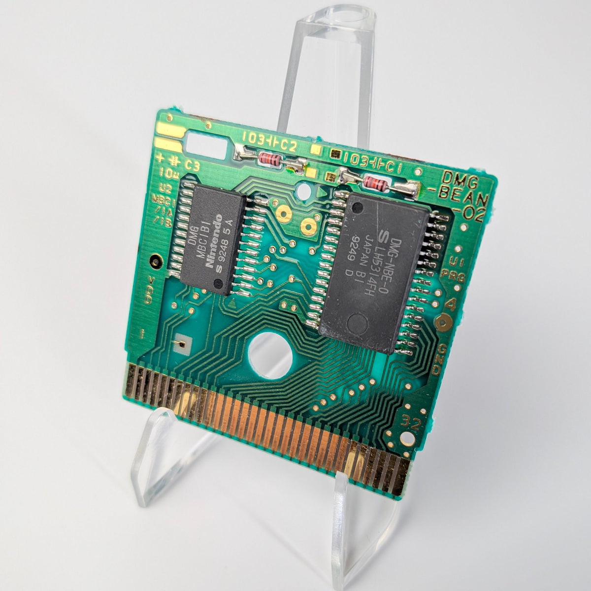 Green electronic circuit board on a clear stand against a white background
