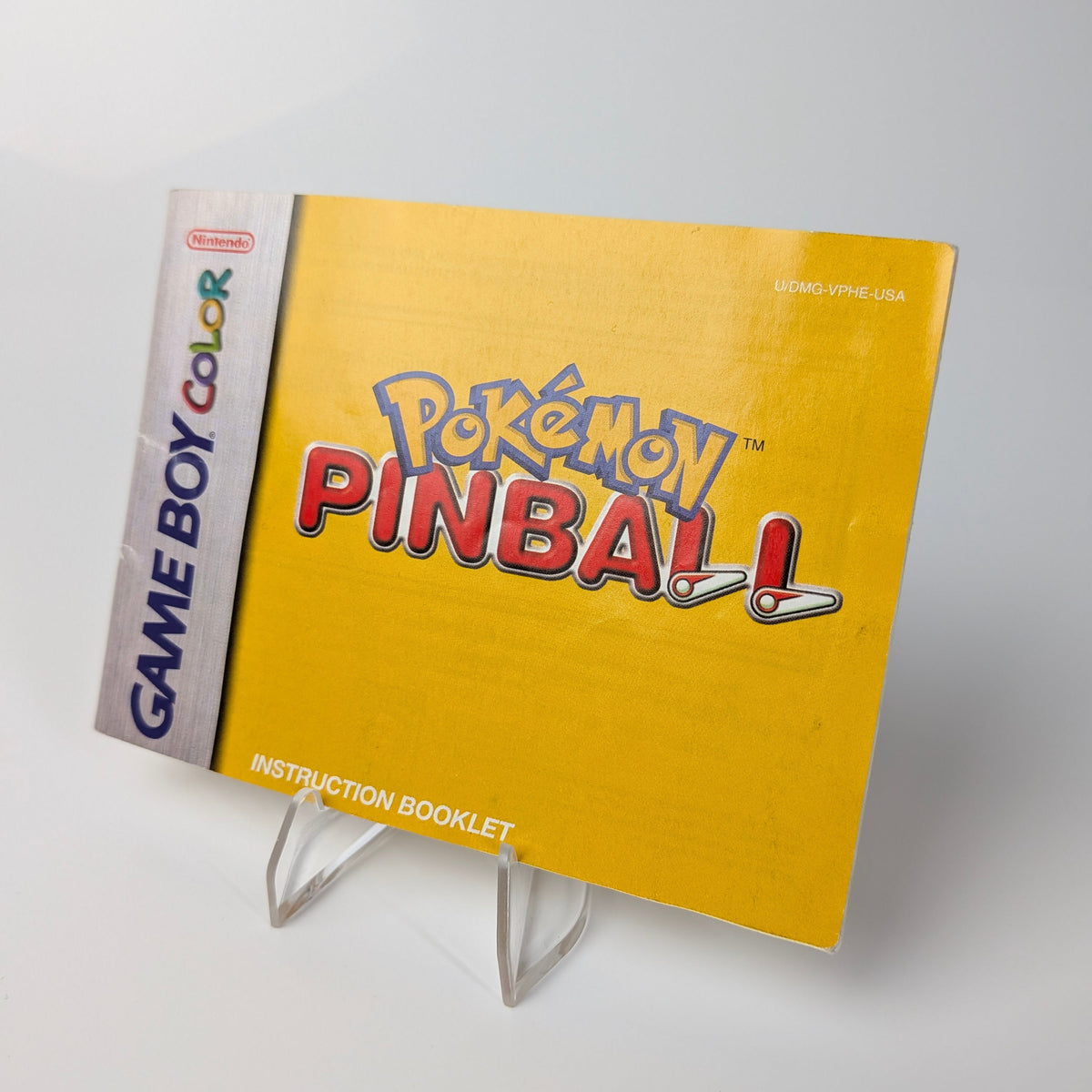 Pokémon Pinball instruction booklet for Game Boy Color on a stand against a white background