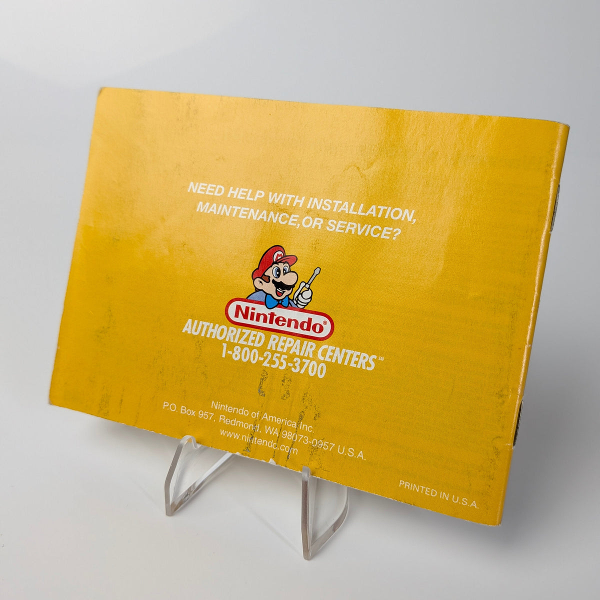 Yellow Nintendo repair center sign on a stand with a white background