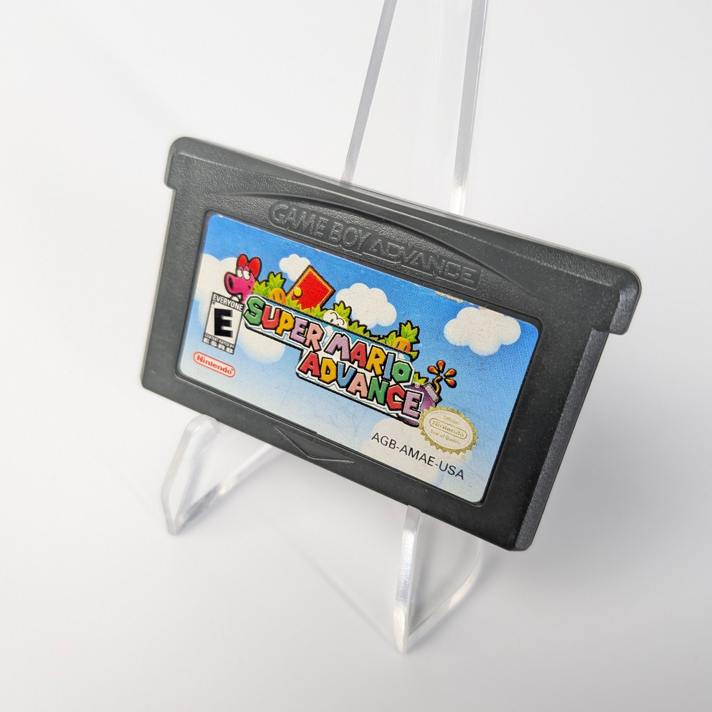 Game Boy Advance cartridge of 'Super Mario Advance' on a stand with a white background